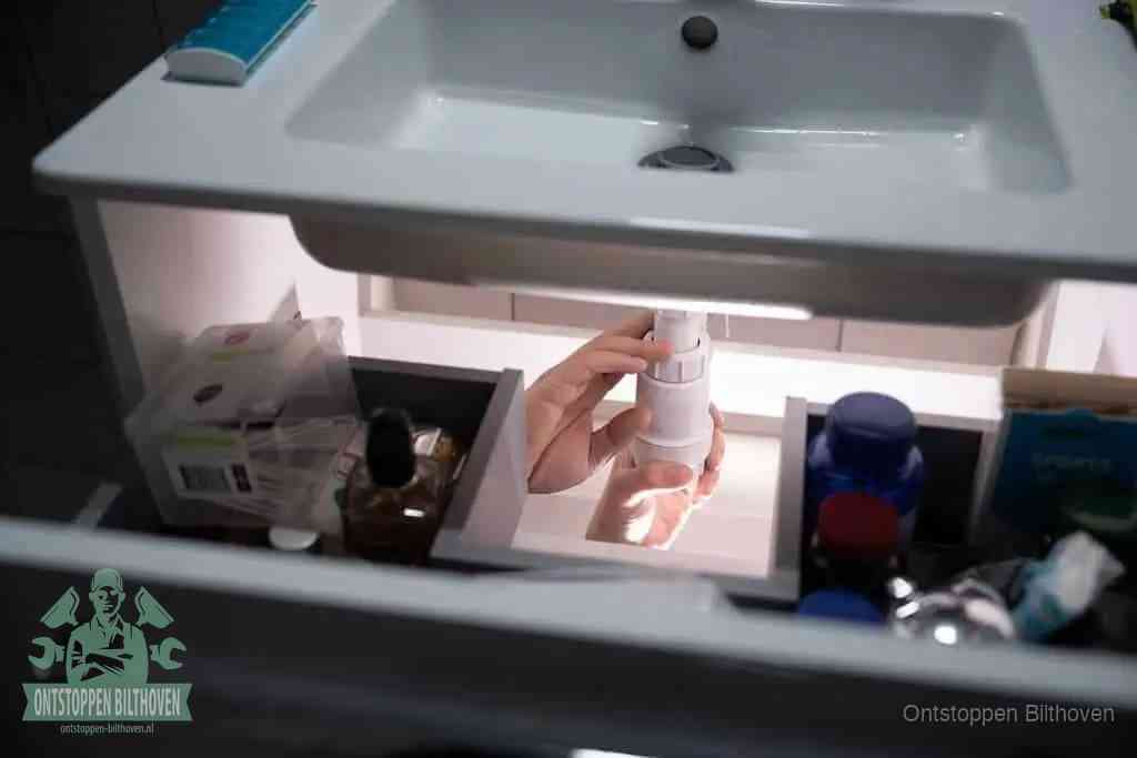 Een pompfles met zeep boven een wastafel, de heet water en afwasmiddel-methode om een vetprop in de afvoer los te maken in Bilthoven