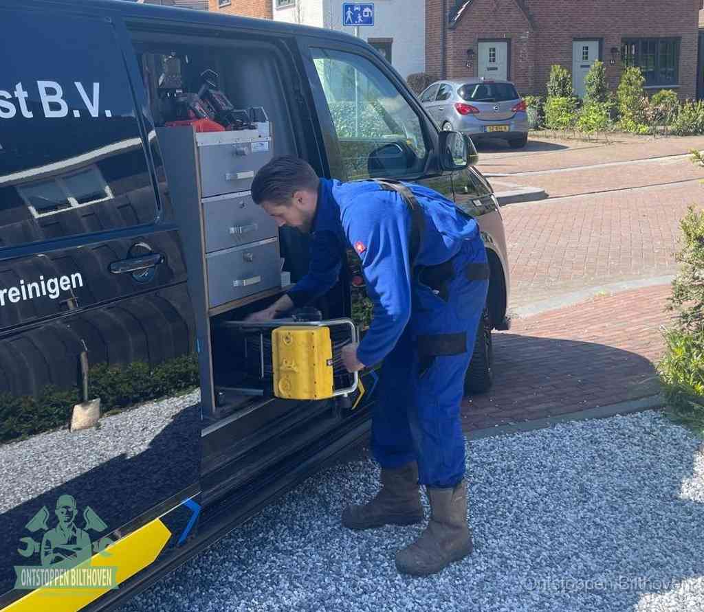 Een monteur pakt buiten op de oprit gereedschap uit de bedrijfsbus, het moment om een professional in te schakelen voor een verstopte afvoer in Bilthoven