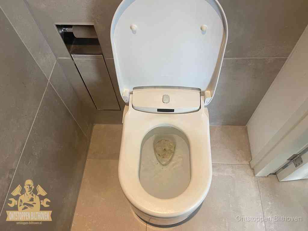 Een wit hangtoilet waarin een prop wc-papier op het water blijft drijven, een duidelijk signaal van een verstopte wc in Bilthoven