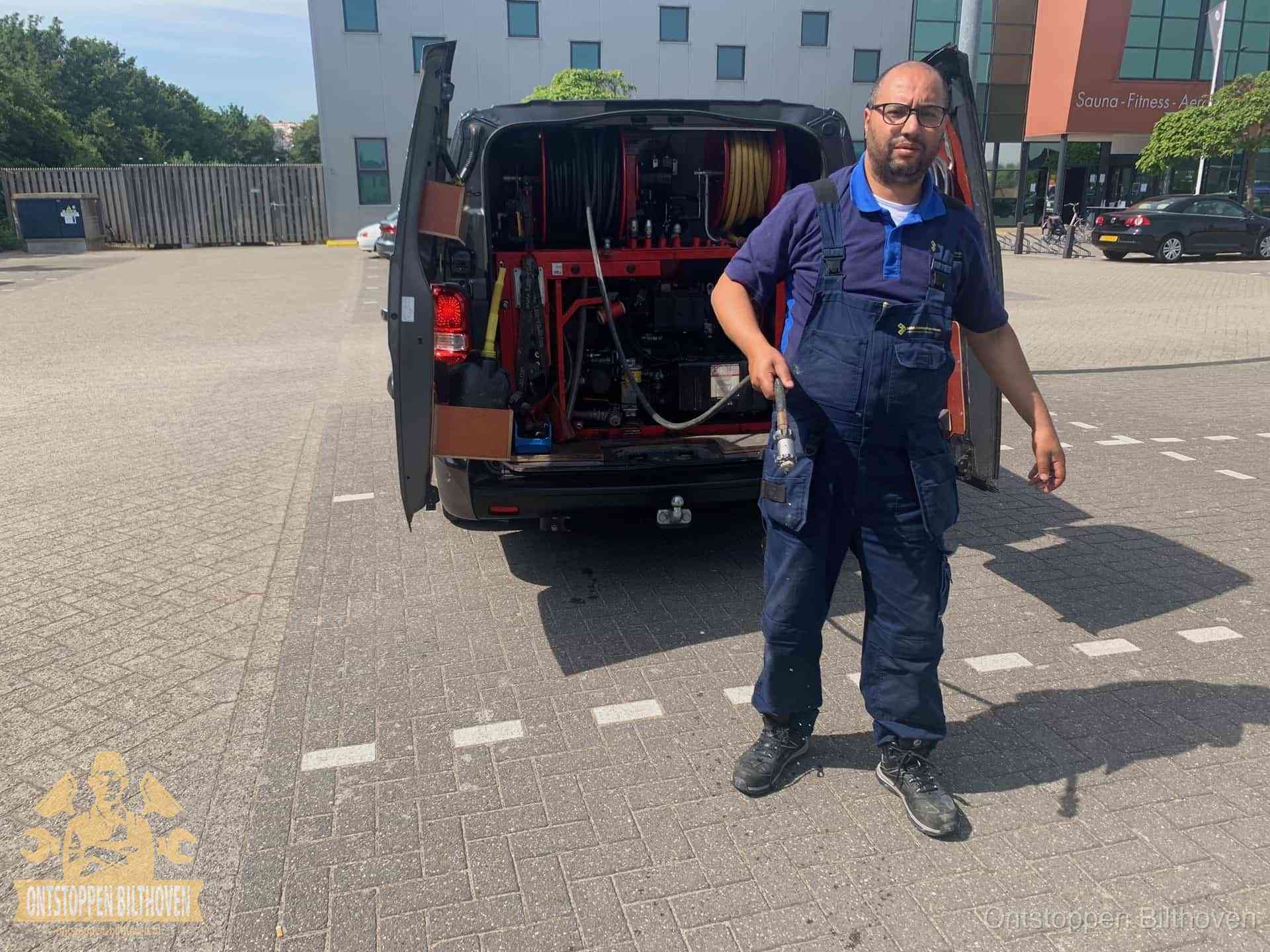 Een monteur bij zijn bestelbus met een hogedruk- en rioolreinigingsunit, klaar om de oorzaak van terugkerende wc-verstoppingen aan te pakken in Bilthoven