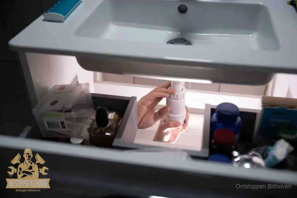 Een pompfles met zeep boven een wastafel in de toiletruimte, de warm water en afwasmiddel-methode om de wc te ontstoppen in Bilthoven