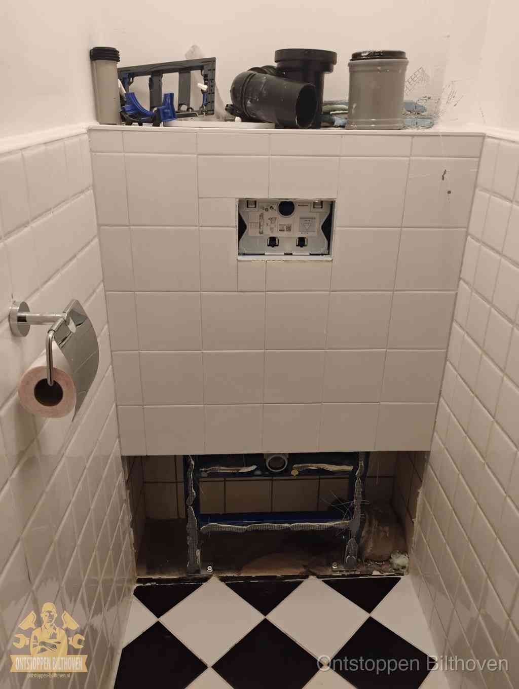 Een toiletruimte waar het hangtoilet en de inbouwreservoir-onderdelen zijn vrijgelegd voor onderhoud, periodiek nazicht voorkomt een wc-verstopping in Bilthoven